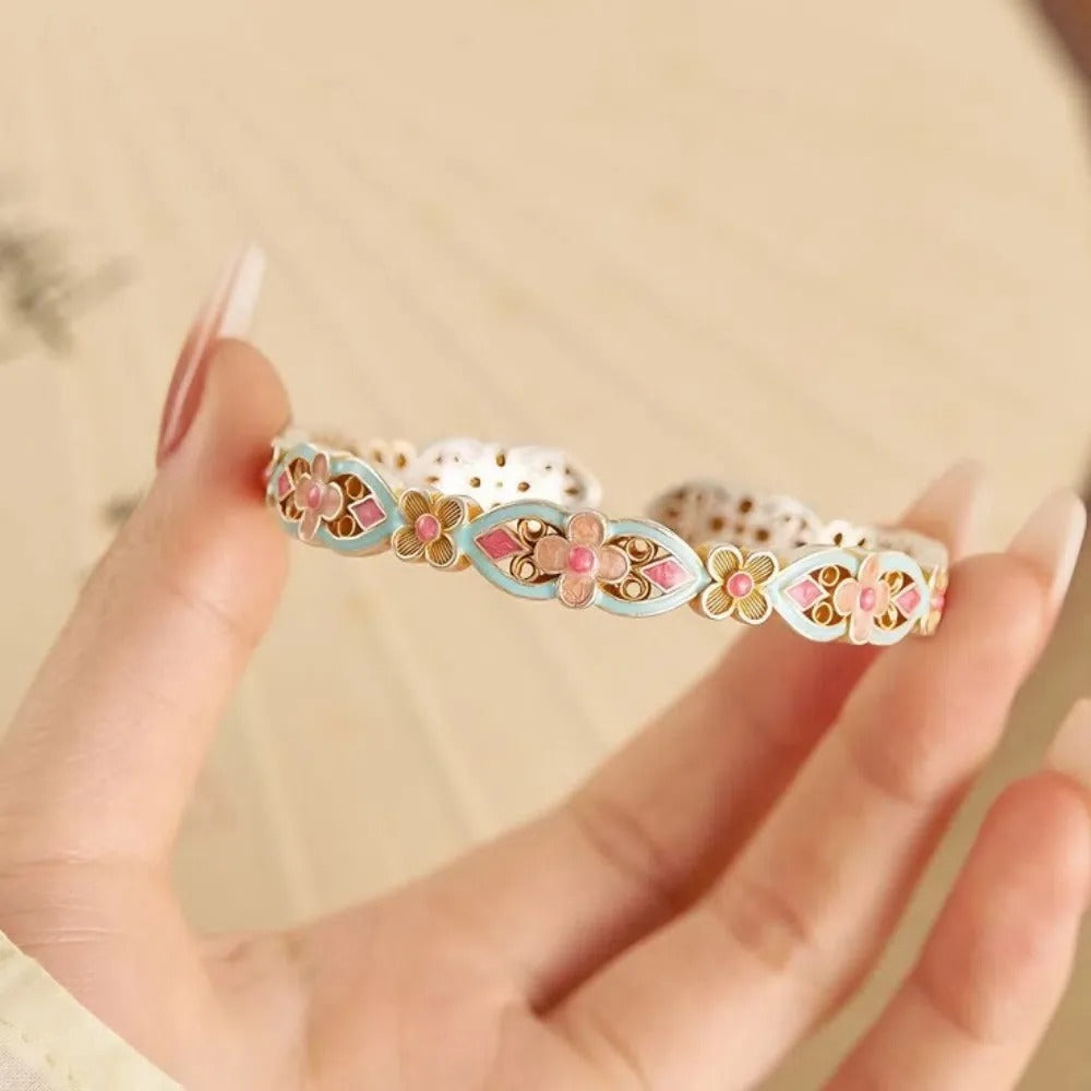 A hand holds the Handicraft Bracelet Classic Traditional Flower Bangle Silver 925, featuring colorful floral enamel designs in pink, blue, and yellow with intricate detailing, set against a soft, neutral background.